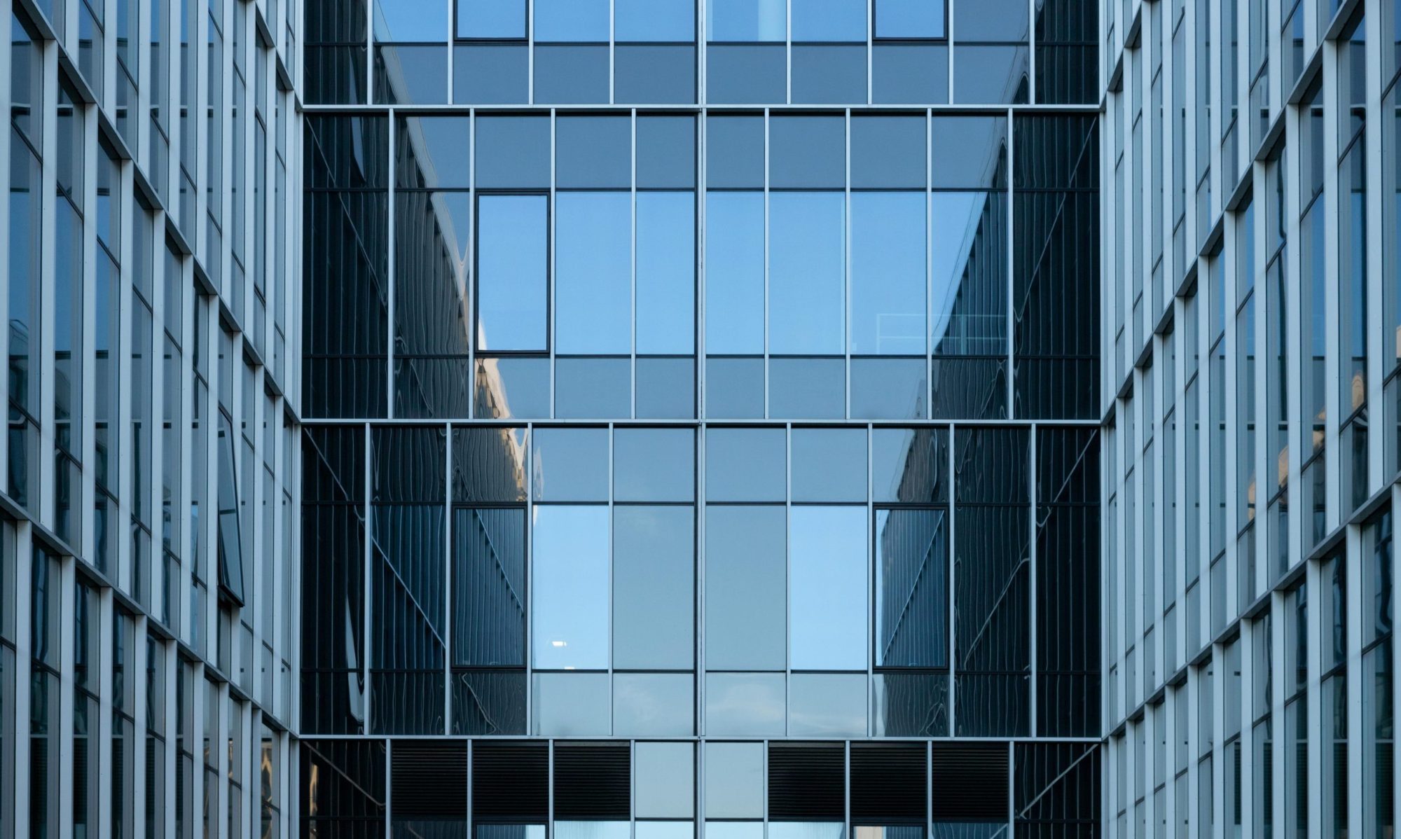 Contemporary building facade with reflective glass windows in an urban environment.